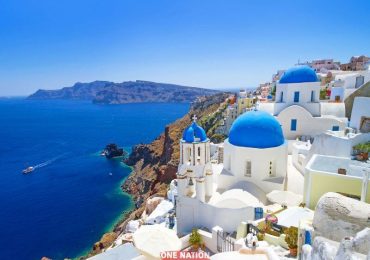 Breathtaking aerial view of Santorini Island featuring white-washed buildings with blue domes overlooking the Aegean Sea.