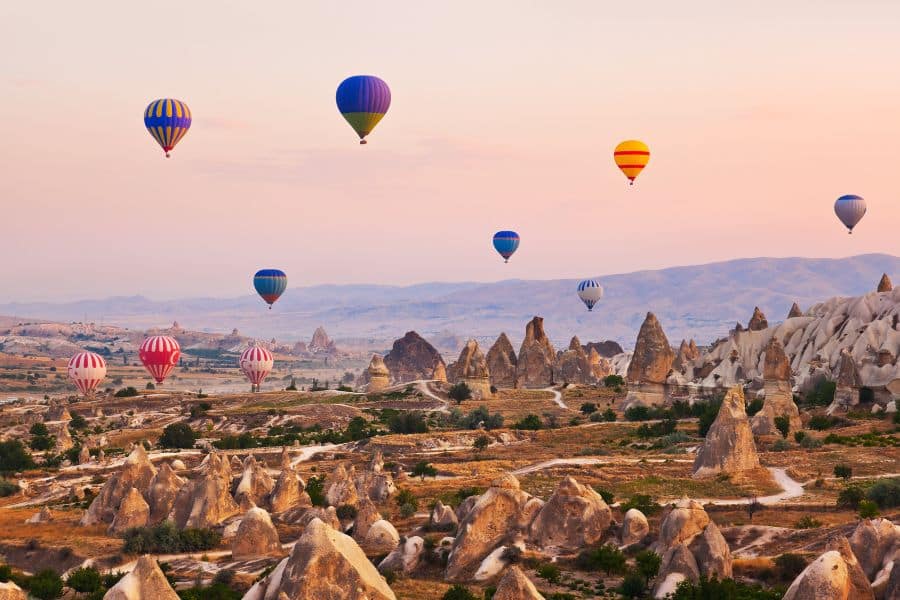 Hot air balloons soaring over the breathtaking rock formations and fairy chimneys of Cappadocia, Turkey, during sunrise