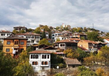 Traditional Ottoman-style Safranbolu houses with white facades, red-tiled roofs, and wooden details, nestled on a hillside.