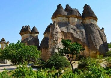 Iconic fairy chimneys in Cappadocia, Turkey, featuring unique cone-shaped rock formations surrounded by lush greenery.