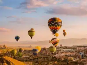 View of colorful hot air balloons flying over Cappadocia's unique landscapes, perfect for Turkey tours