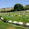 Ariburnu Cemetery in Gallipoli, rows of white headstones against serene landscape.