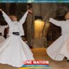 Three individuals performing a traditional Sufi whirling dance in long white robes and tall hats inside a historic building.