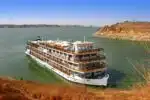 Luxurious Nile cruise ship sailing past ancient Egyptian landmarks.