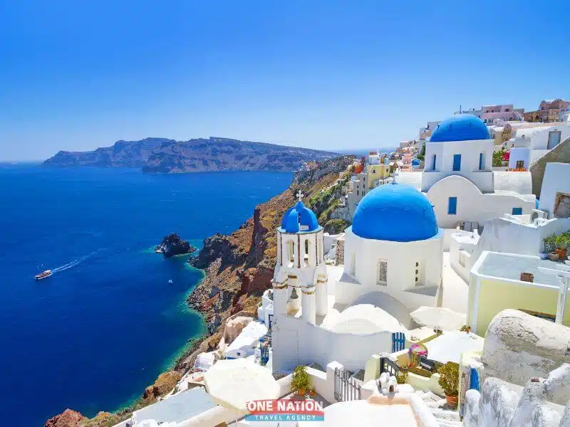 Breathtaking aerial view of Santorini Island featuring white-washed buildings with blue domes overlooking the Aegean Sea.
