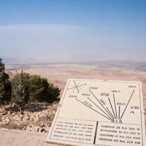 a sign on a hill with trees in the background