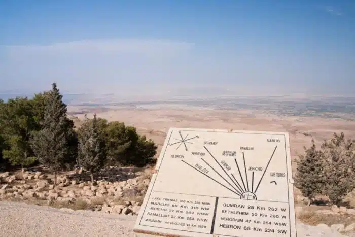 a sign on a hill with trees in the background