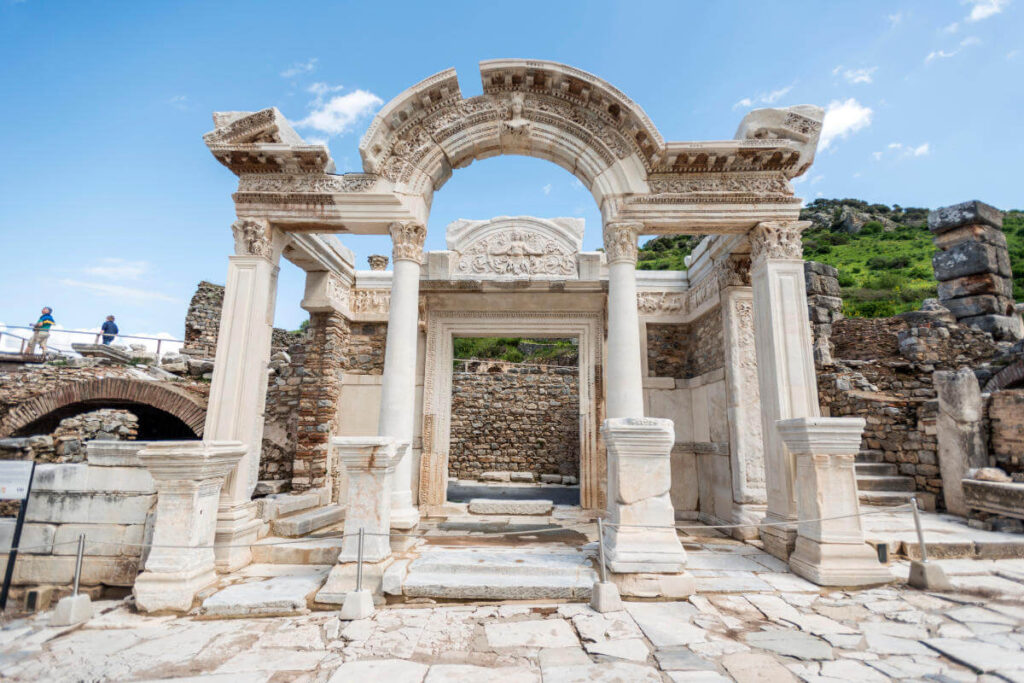 Restored marble facade of the Temple of Hadrian in Ephesus with intricate carvings and curved arch detail.