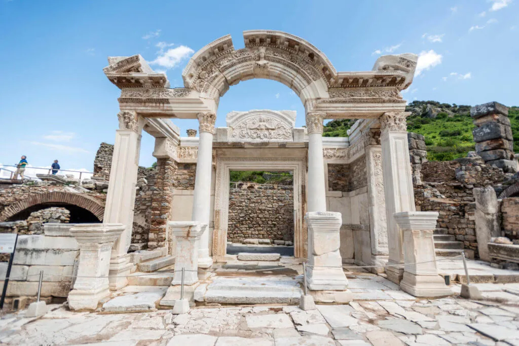 Restored marble facade of the Temple of Hadrian in Ephesus with intricate carvings and curved arch detail.