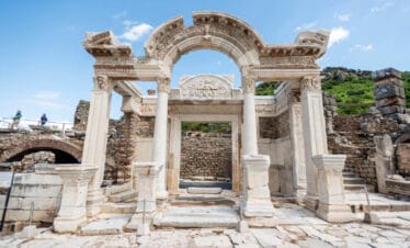 Restored marble facade of the Temple of Hadrian in Ephesus with intricate carvings and curved arch detail.