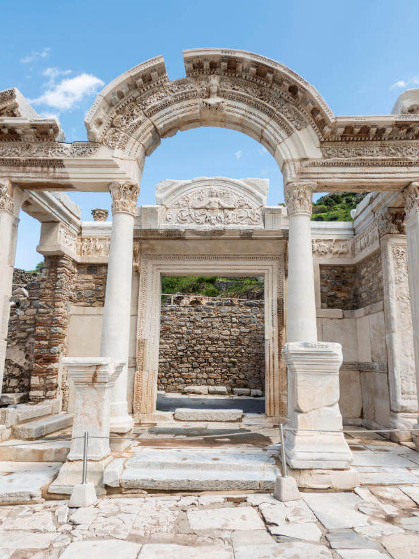Restored marble facade of the Temple of Hadrian in Ephesus with intricate carvings and curved arch detail.