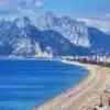 Panoramic view of the Antalya coastline featuring the calm sea and distant mountains under a bright sky.
