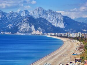 Panoramic view of the Antalya coastline featuring the calm sea and distant mountains under a bright sky.