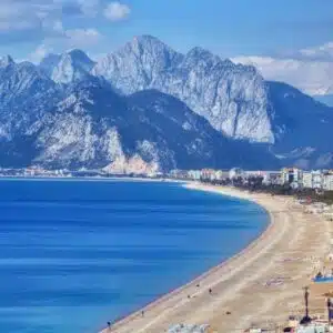 Panoramic view of the Antalya coastline featuring the calm sea and distant mountains under a bright sky.