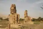Majestic Colossi of Memnon statues standing tall in Luxor, Egypt, against a clear blue sky.