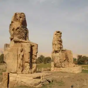 Majestic Colossi of Memnon statues standing tall in Luxor, Egypt, against a clear blue sky.