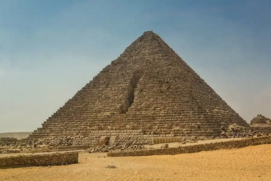 Tourists exploring the base of the Pyramid of Menkaure against a desert backdrop.