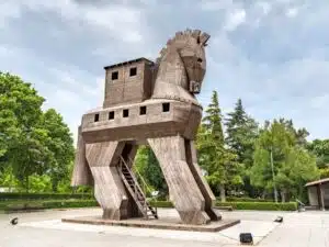 Wooden Trojan Horse sculpture, exterior view, with intricate carvings and large hollow body, set against a clear sky.