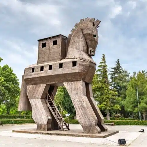 Wooden Trojan Horse sculpture, exterior view, with intricate carvings and large hollow body, set against a clear sky.