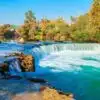 Manavgat Waterfall in Antalya, showing cascading waters surrounded by lush greenery and rocks.