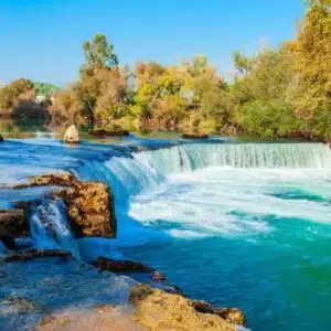 Manavgat Waterfall in Antalya, showing cascading waters surrounded by lush greenery and rocks.