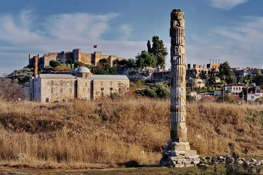 Ruins of the Temple of Artemis at Ephesus under a vibrant sunset, casting long shadows over ancient stones.