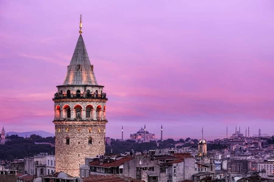 Purple-hued Galata Tower against evening sky, iconic medieval stone monument.