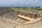 Ruins of ancient Pamukkale Theatre in Turkey, showcasing well-preserved stone seats and stage.