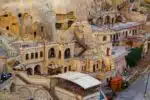 Stone-walled cave hotel room in Cappadocia with cozy furnishings, traditional decor, and ambient lighting.