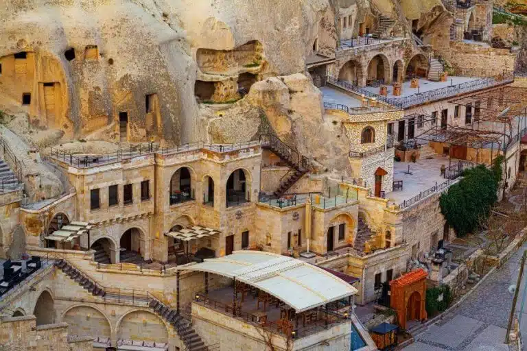 Stone-walled cave hotel room in Cappadocia with cozy furnishings, traditional decor, and ambient lighting.