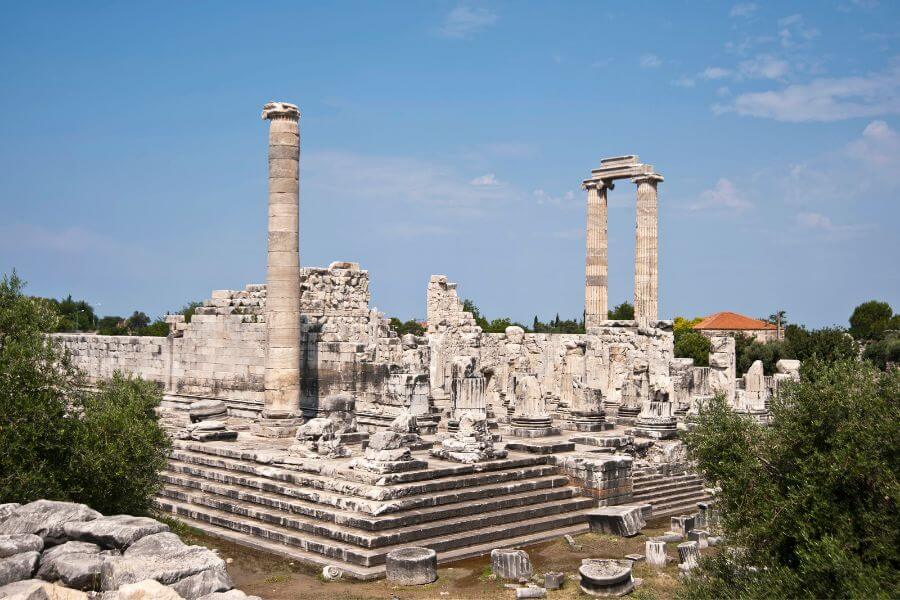 Ruins of the Temple of Apollo at Didyma, featuring towering stone columns and scattered ancient debris."