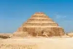 View of Saqqara Necropolis in Egypt, showcasing ancient pyramid structures, tombs, and desert landscape under a clear sky.