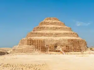 View of Saqqara Necropolis in Egypt, showcasing ancient pyramid structures, tombs, and desert landscape under a clear sky.