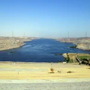 Panoramic view of the Aswan High Dam, showcasing its massive concrete structure spanning the Nile River under a clear blue sky.