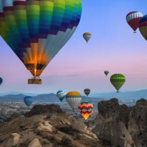 Cappadocia hot air balloons rising at dawn over unique rock formations.