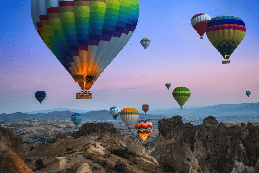 Cappadocia hot air balloons rising at dawn over unique rock formations.