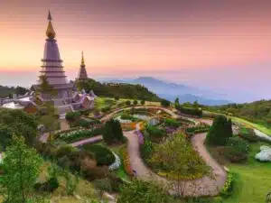 Panoramic view of Doi Inthanon National Park with lush green forests, cascading waterfalls, and mist-covered mountain peaks in Thailand.