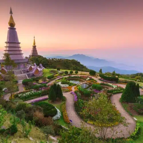 Panoramic view of Doi Inthanon National Park with lush green forests, cascading waterfalls, and mist-covered mountain peaks in Thailand.