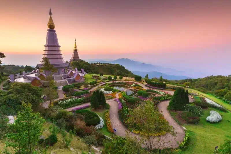 Panoramic view of Doi Inthanon National Park with lush green forests, cascading waterfalls, and mist-covered mountain peaks in Thailand.