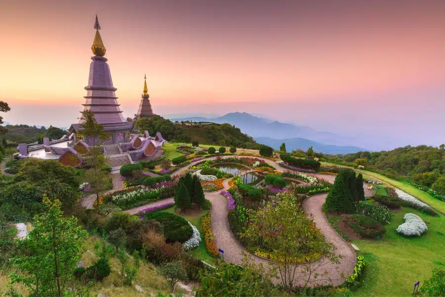 Panoramic view of Doi Inthanon National Park with lush green forests, cascading waterfalls, and mist-covered mountain peaks in Thailand.