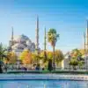 Exterior view of the Blue Mosque in Istanbul, showcasing its grand domes and six slender minarets against a clear sky.