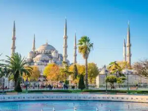 Exterior view of the Blue Mosque in Istanbul, showcasing its grand domes and six slender minarets against a clear sky.