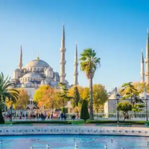 Exterior view of the Blue Mosque in Istanbul, showcasing its grand domes and six slender minarets against a clear sky.