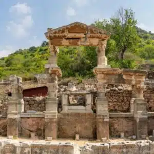 Ancient Fountain of Trajan in Ephesus, Turkey, featuring intricate Roman-era stonework and columns, surrounded by historical ruins.