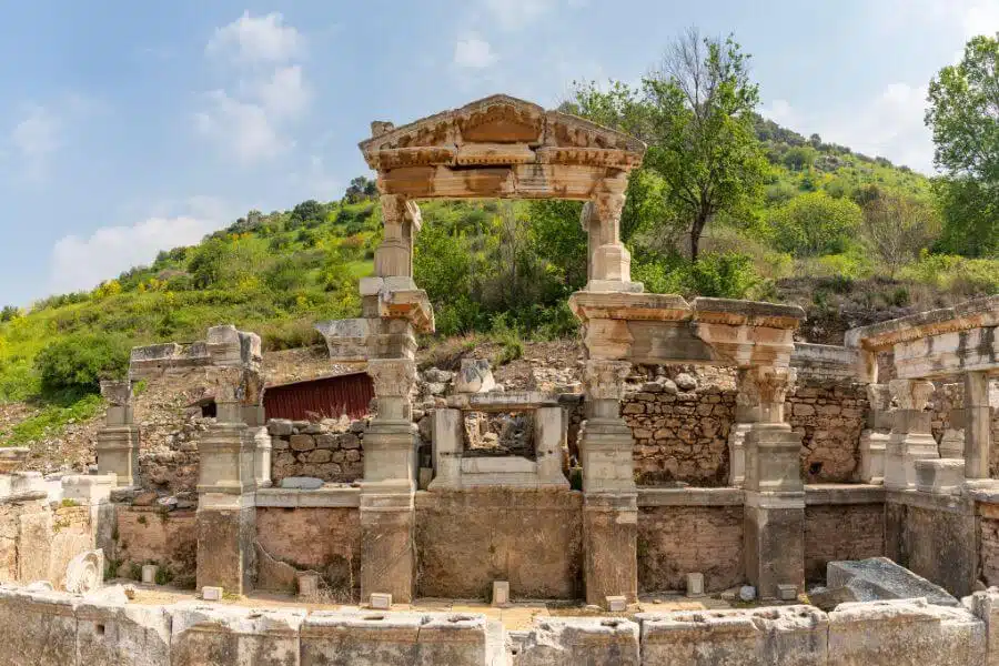 Ancient Fountain of Trajan in Ephesus, Turkey, featuring intricate Roman-era stonework and columns, surrounded by historical ruins.