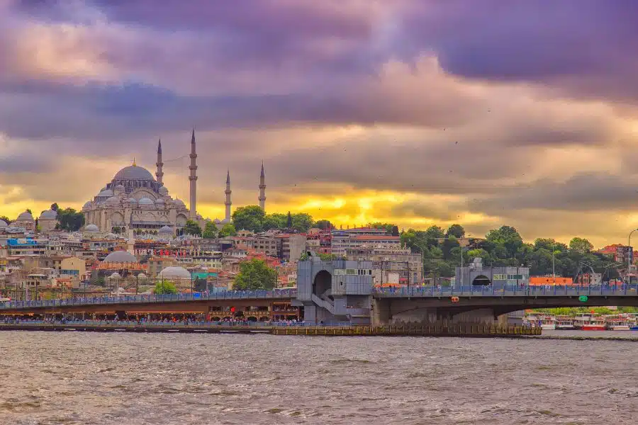 Süleymaniye Mosque in Istanbul viewed from Galata Bridge, showcasing its grand domes and minarets against the skyline.