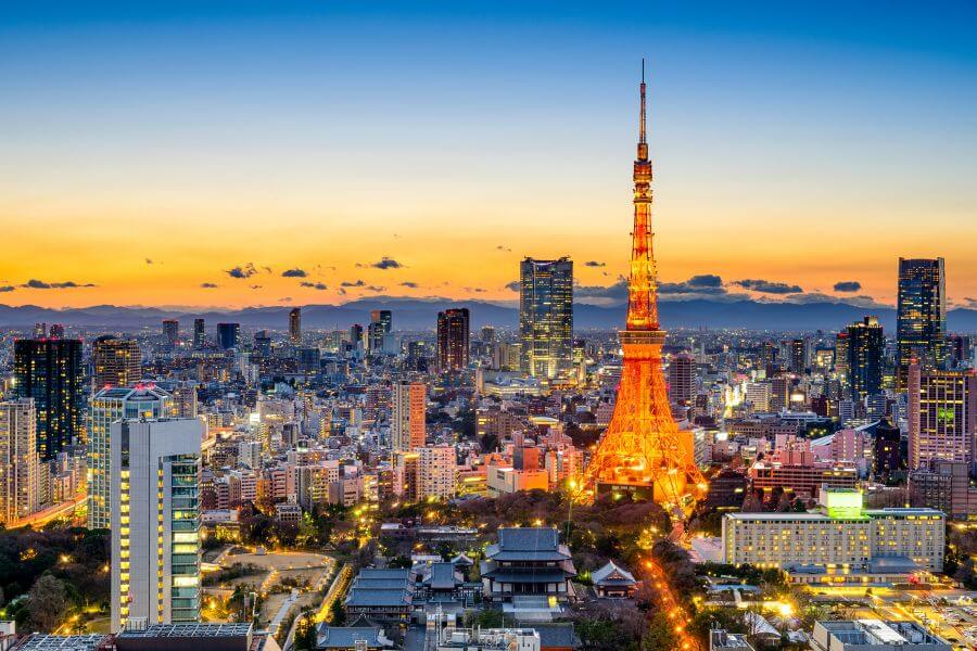 Red and white Tokyo Tower, inspired by the Eiffel Tower, illuminated at night against the city skyline.