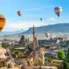 Hot air balloon floating over a mosque in Goreme at sunrise, showcasing Cappadocia's stunning landscape.