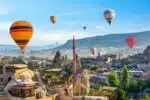 Hot air balloon floating over a mosque in Goreme at sunrise, showcasing Cappadocia's stunning landscape.