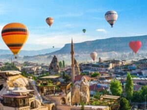 Hot air balloon floating over a mosque in Goreme at sunrise, showcasing Cappadocia's stunning landscape.